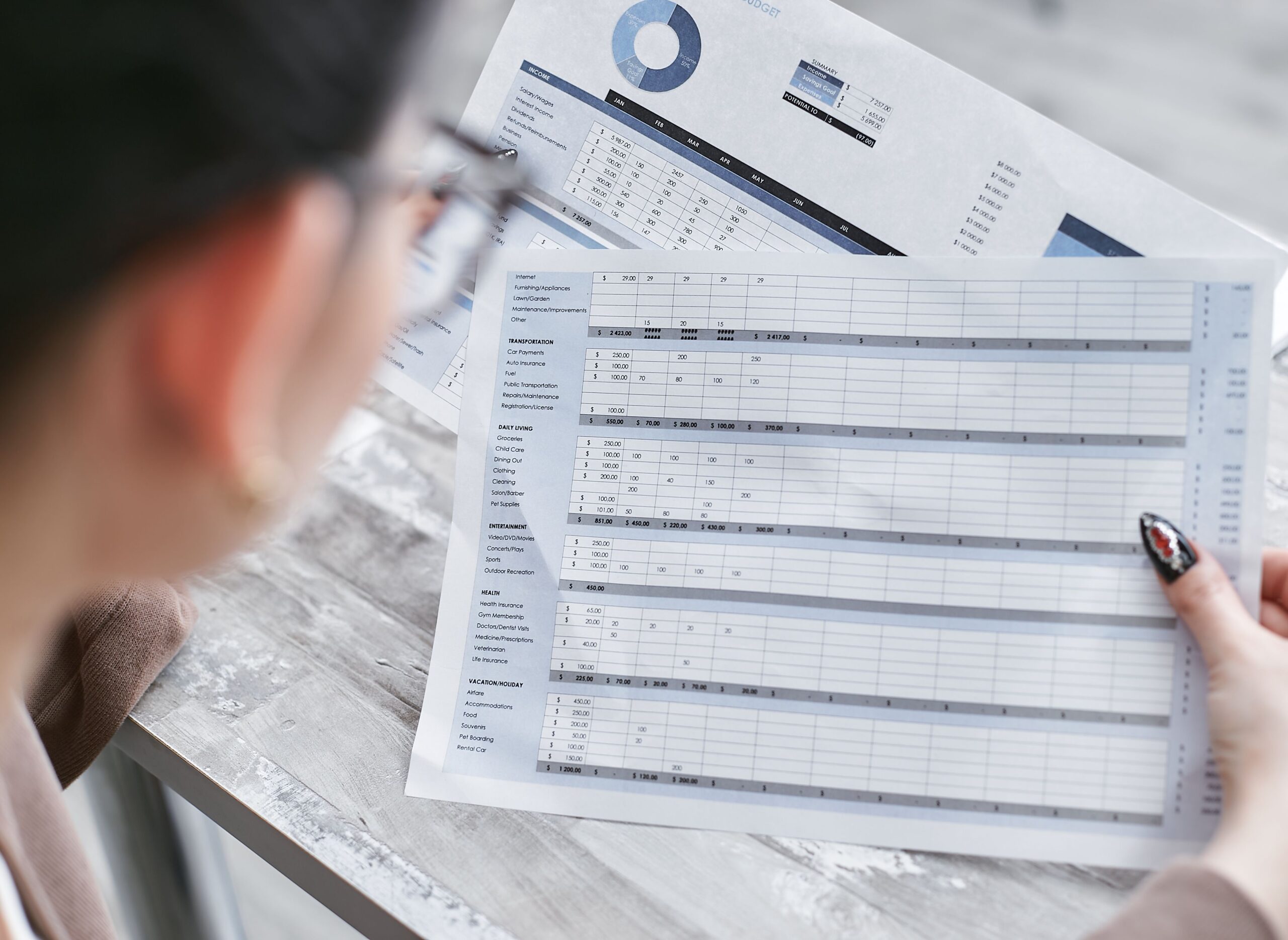 A hand points to rows of data on a printed spreadsheet, illustrating an audit trail review.